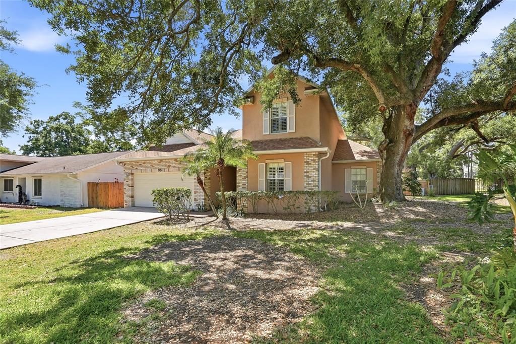 A two-story house with a tan stucco exterior, brick accents, and a two-car garage — 1934 OLD SAWMILL ROAD, BRANDON, FL