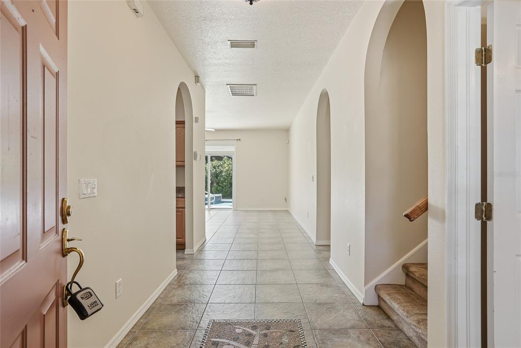 A tiled entryway leads to a hallway with arched openings, a staircase, and a sliding door — 1934 OLD SAWMILL ROAD, BRANDON, FL