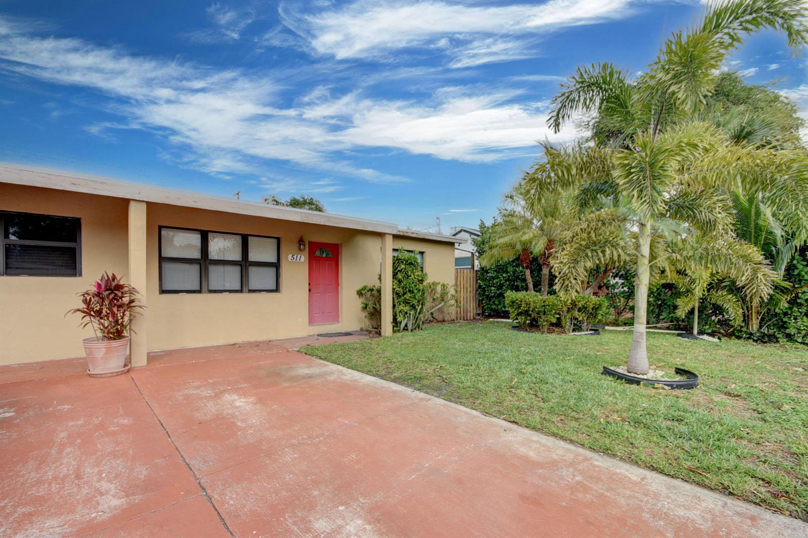 A single-story house with a red front door, a concrete driveway, and a palm tree — 511 Minnesota Street, Lantana FL 33462, LANTANA, FL
