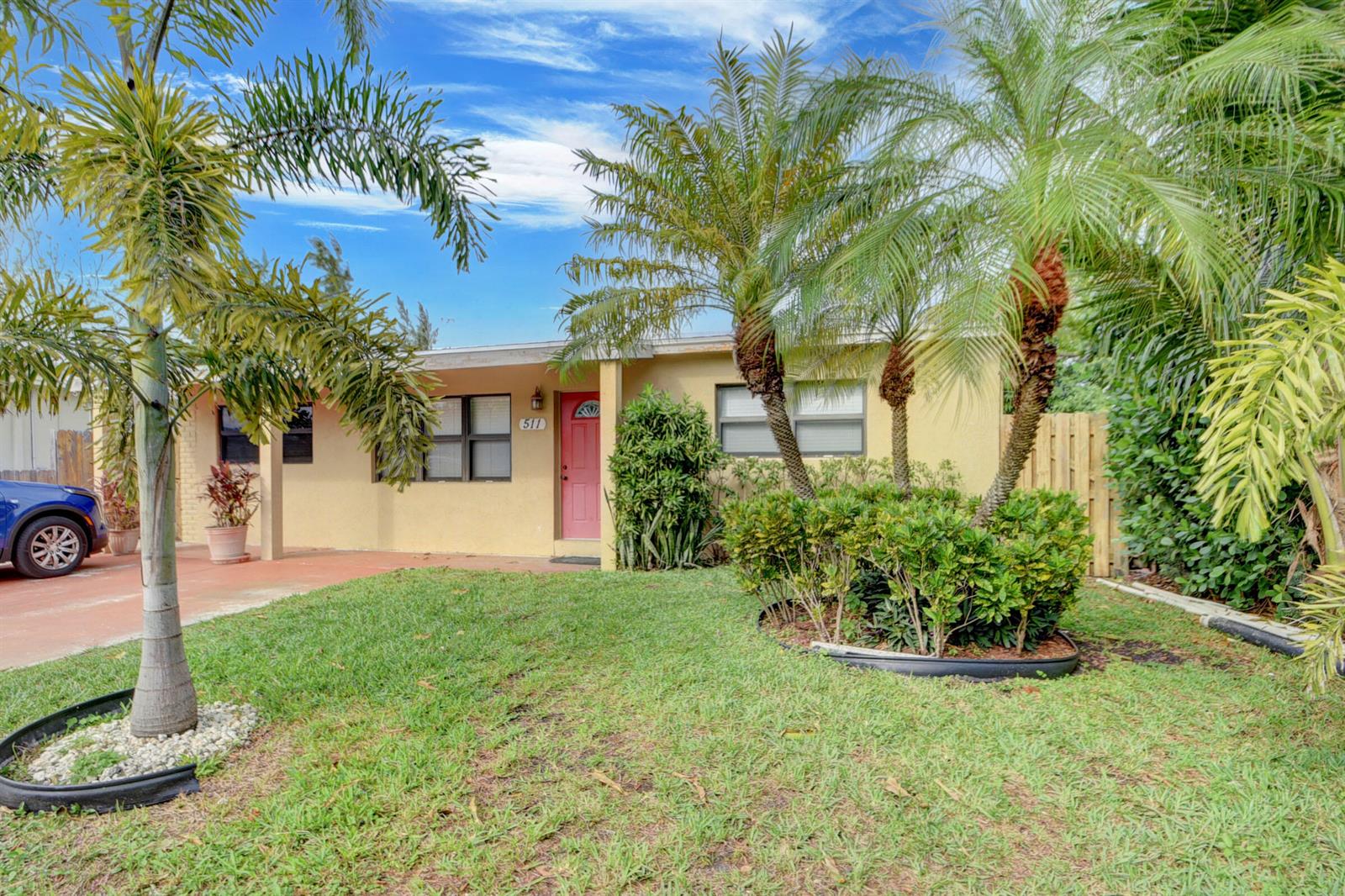 A single-story yellow house with a red door, palm trees, and a front lawn — 511 Minnesota Street, Lantana FL 33462, LANTANA, FL