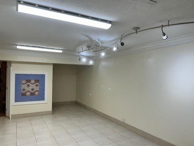 An empty room with tiled floors, track lighting, and a decorative framed wall art piece — 1775 Blount Road # 409, Pompano Beach FL 33069, POMPANO BEACH, FL