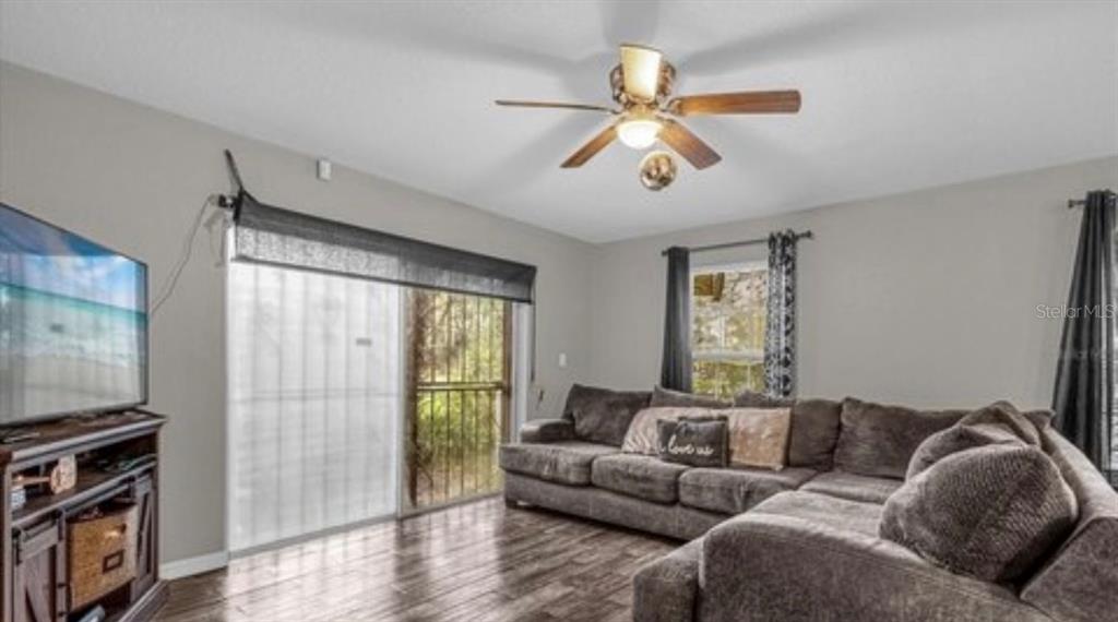 A living room features a sectional sofa, wood-look flooring, a ceiling fan, and sliding glass doors — 1783 FLORES COURT, ORLANDO, FL