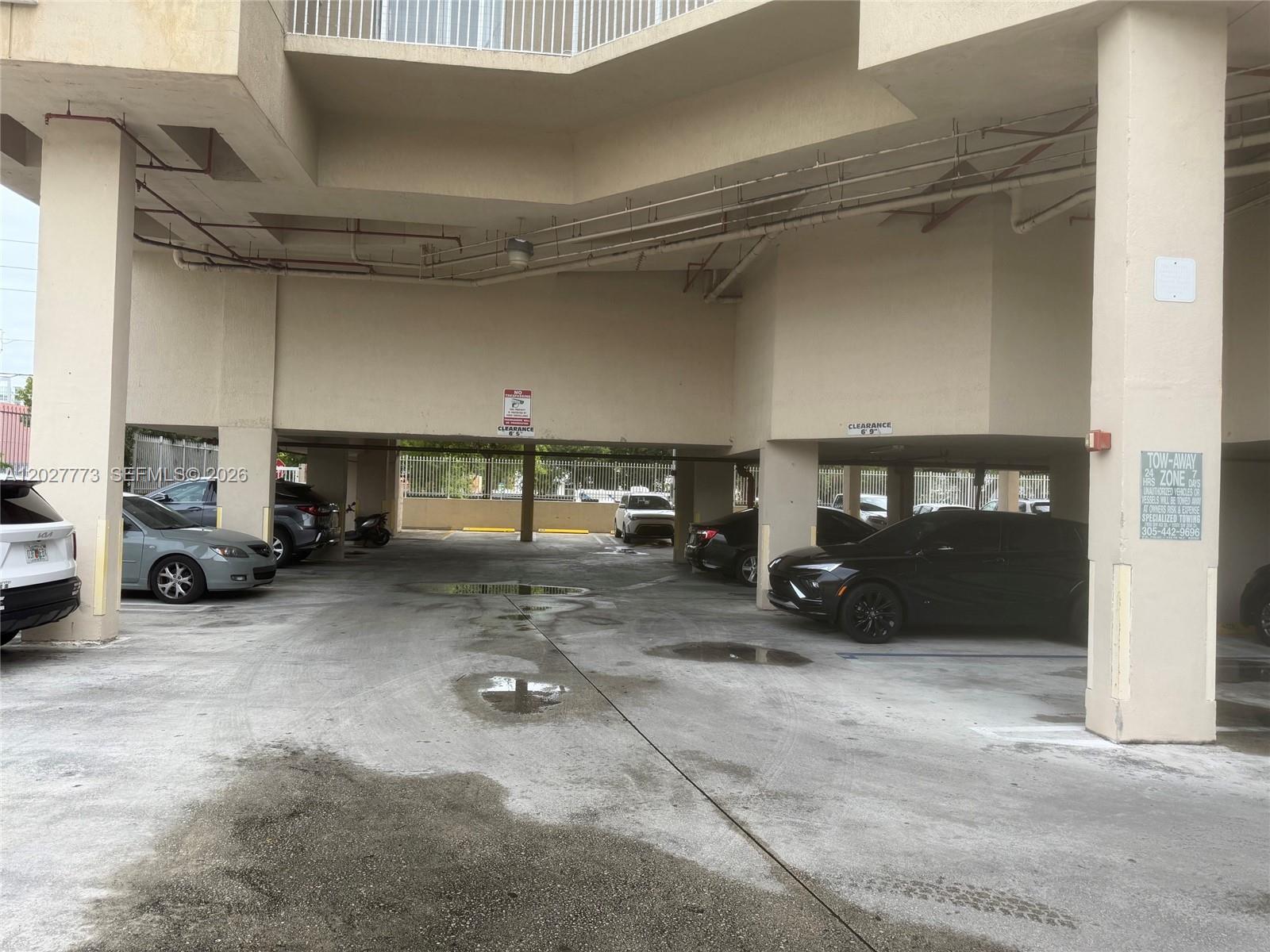 A covered parking garage features concrete pillars, multiple parked vehicles, and low-clearance signage — 102 SW 6th Ave # 501, Miami FL 33130, MIAMI, FL
