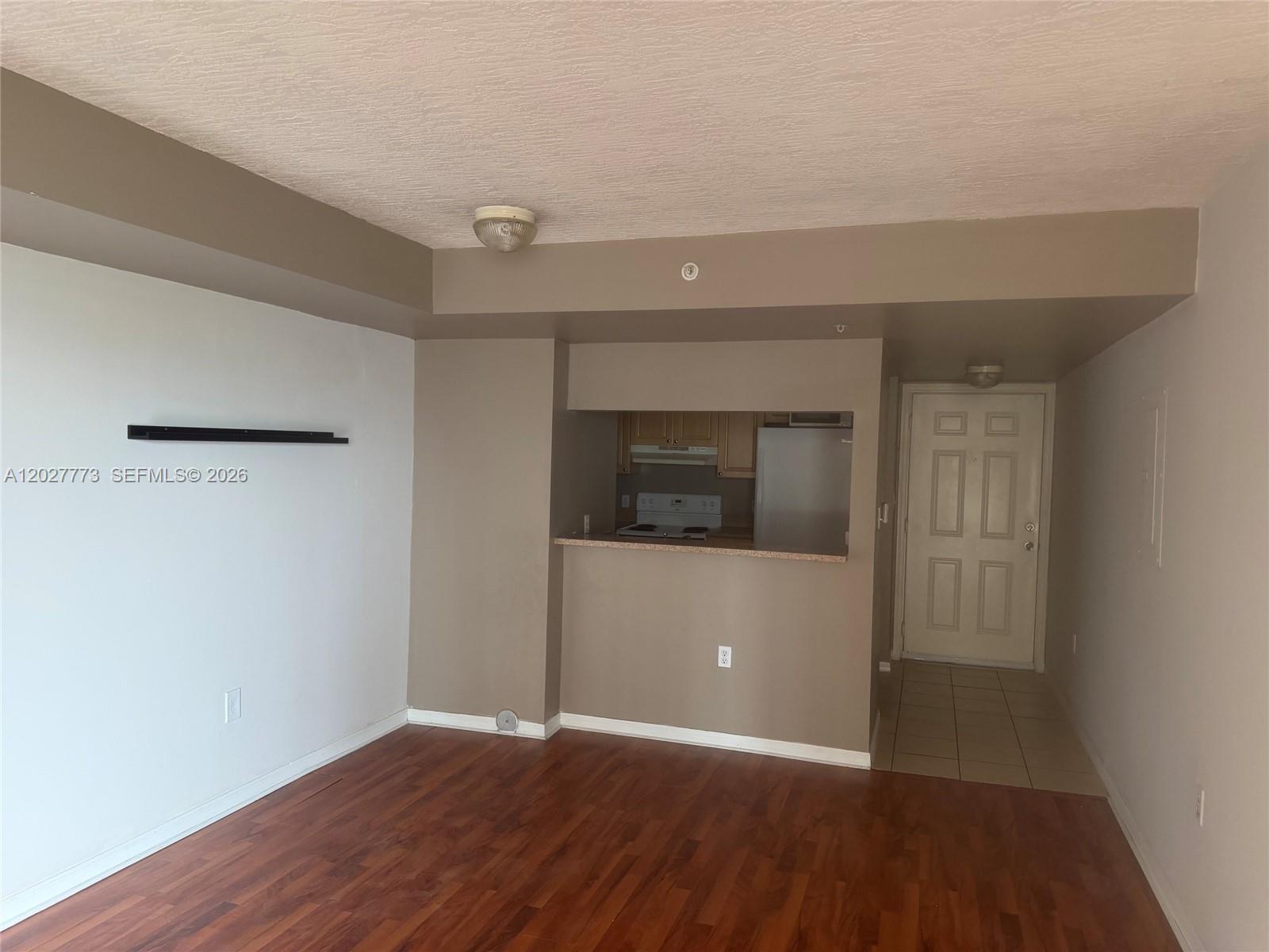 An interior view shows a living area with wood flooring, a pass-through kitchen, and entryway — 102 SW 6th Ave # 501, Miami FL 33130, MIAMI, FL