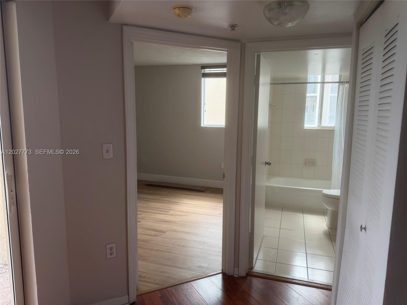 A hallway leads to a bedroom with wood-look flooring and a tiled bathroom — 102 SW 6th Ave # 501, Miami FL 33130, MIAMI, FL