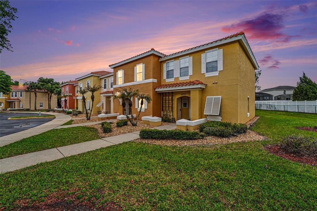 A two-story yellow stucco townhouse with a tiled roof and a front walkway — 1075 PARK RIDGE CIRCLE, KISSIMMEE, FL