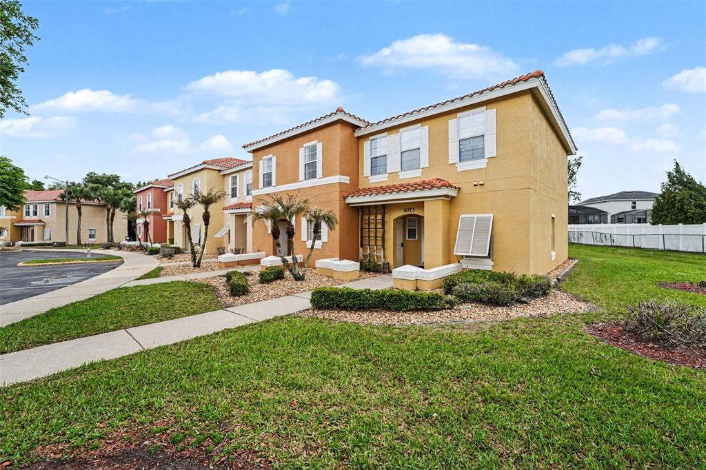 A two-story tan stucco townhouse with a tile roof and a small front yard — 1075 PARK RIDGE CIRCLE, KISSIMMEE, FL