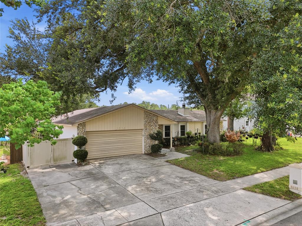 A single-story house with a stone facade, a two-car garage, and a large oak tree — 1610 GLADIOLAS DRIVE, WINTER PARK, FL
