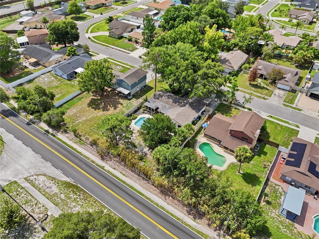 An aerial view shows suburban houses with swimming pools and trees along a paved road — 1610 GLADIOLAS DRIVE, WINTER PARK, FL
