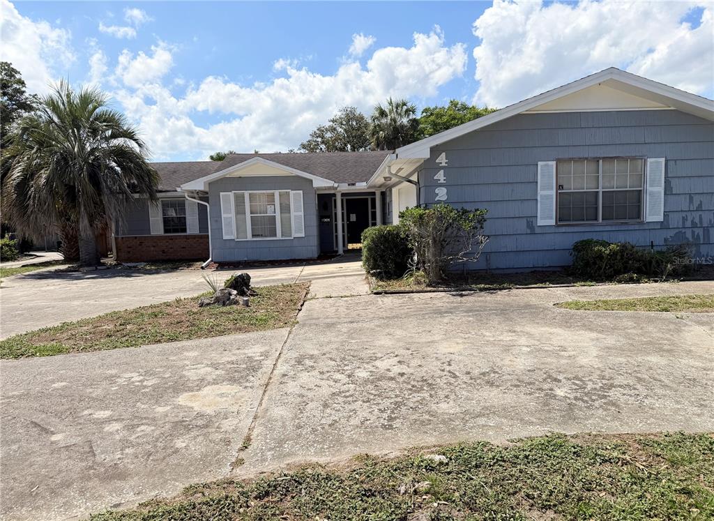 A single-story house with gray siding, a concrete driveway, and a palm tree in front — 4420 TRAVELERS ROAD, JACKSONVILLE, FL
