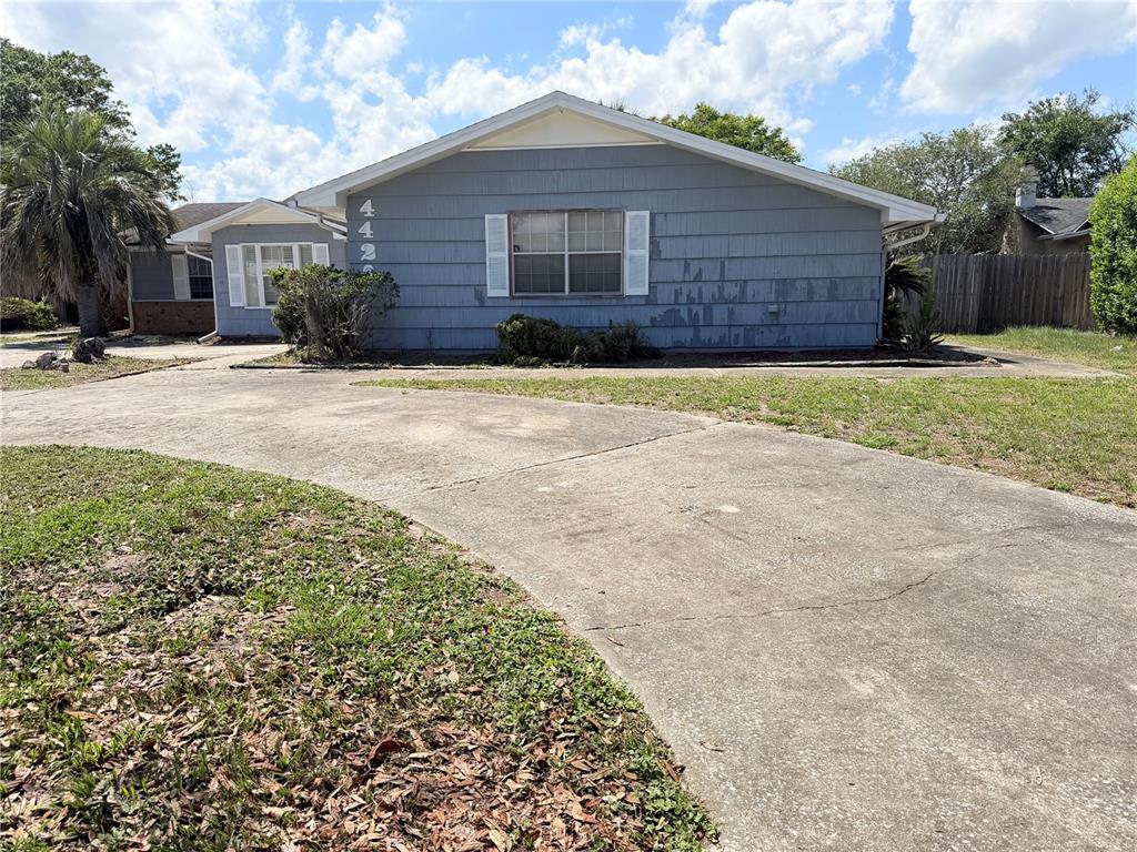 A single-story house with gray siding and a concrete driveway under a cloudy sky — 4420 TRAVELERS ROAD, JACKSONVILLE, FL