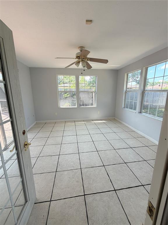 A sunroom with light gray walls, white tiled floors, and a ceiling fan — 4420 TRAVELERS ROAD, JACKSONVILLE, FL
