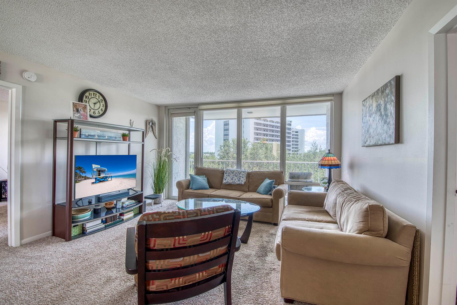 A living room features two beige sofas, a television console, and a large window view — 336 Golfview Road # 518, North Palm Beach FL 33408, NORTH PALM BEACH, FL