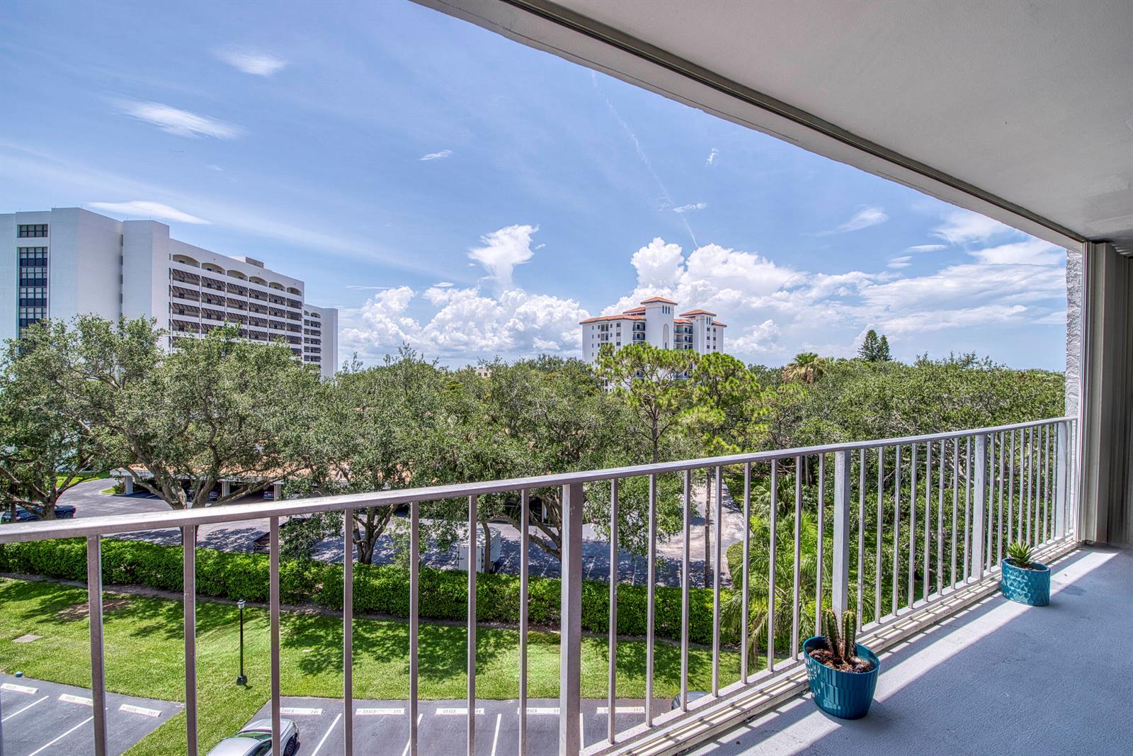A balcony overlooks a parking lot, green trees, and distant high-rise buildings under a blue sky — 336 Golfview Road # 518, North Palm Beach FL 33408, NORTH PALM BEACH, FL