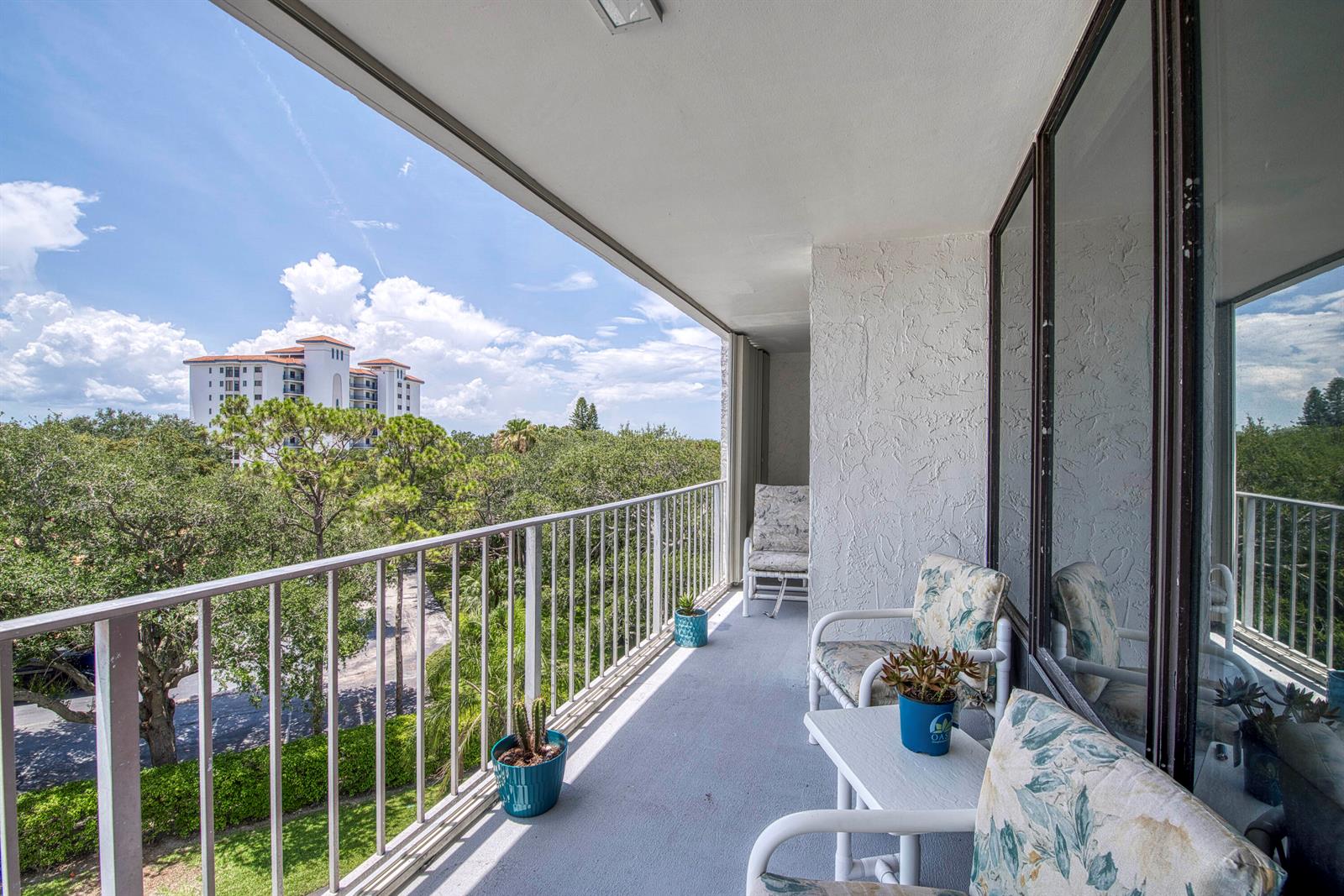 A balcony features white metal railings, patio furniture, potted plants, and a view of trees — 336 Golfview Road # 518, North Palm Beach FL 33408, NORTH PALM BEACH, FL