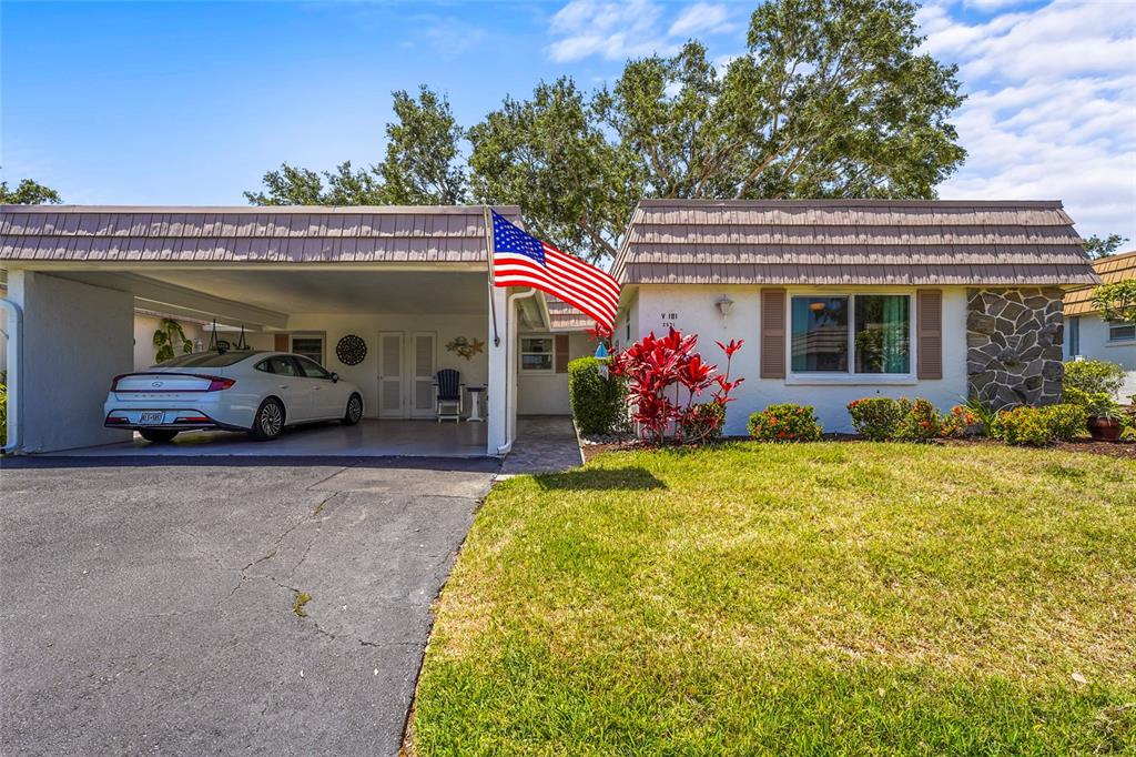 A single-story house with a carport, a white sedan, and an American flag in front — 2531 RIVERBLUFF PARKWAY UNIT V181, SARASOTA, FL
