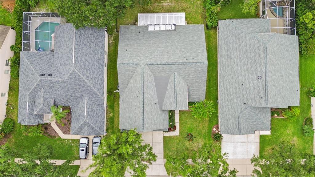An aerial view shows three suburban houses with gray roofs, driveways, and backyard swimming pools — 10217 TIMBERLAND POINT DRIVE, TAMPA, FL