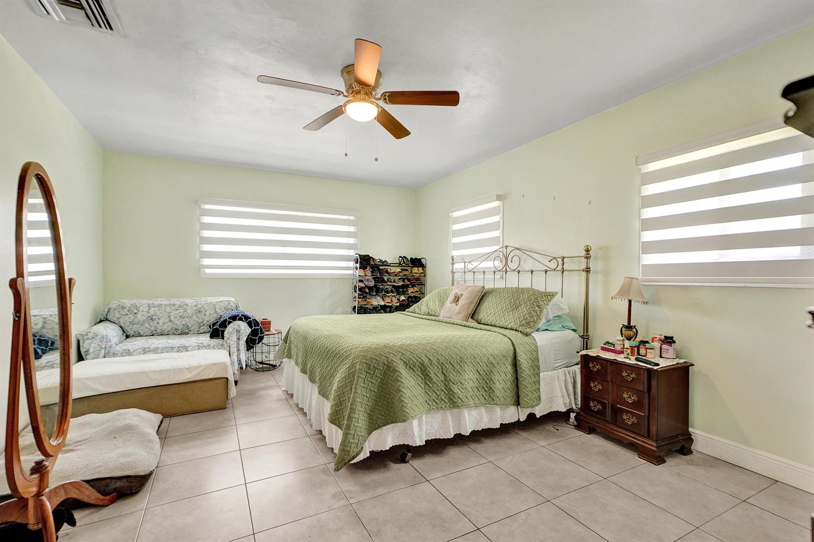 A bedroom with light green walls, tile flooring, a metal bed frame, and a ceiling fan — 1070 NW 149th Street, Miami FL 33168, MIAMI, FL