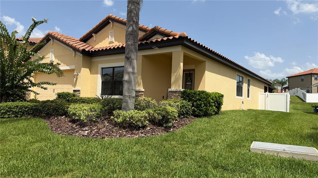 A single-story yellow stucco house with a tiled roof, a palm tree, and landscaping — 1947 ALTAVISTA CIRCLE, LAKELAND, FL