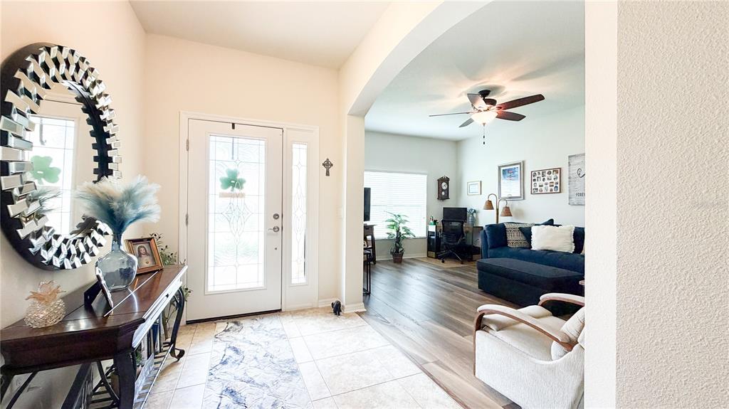 A foyer with a decorative mirror and console table leads into a living room area — 1947 ALTAVISTA CIRCLE, LAKELAND, FL