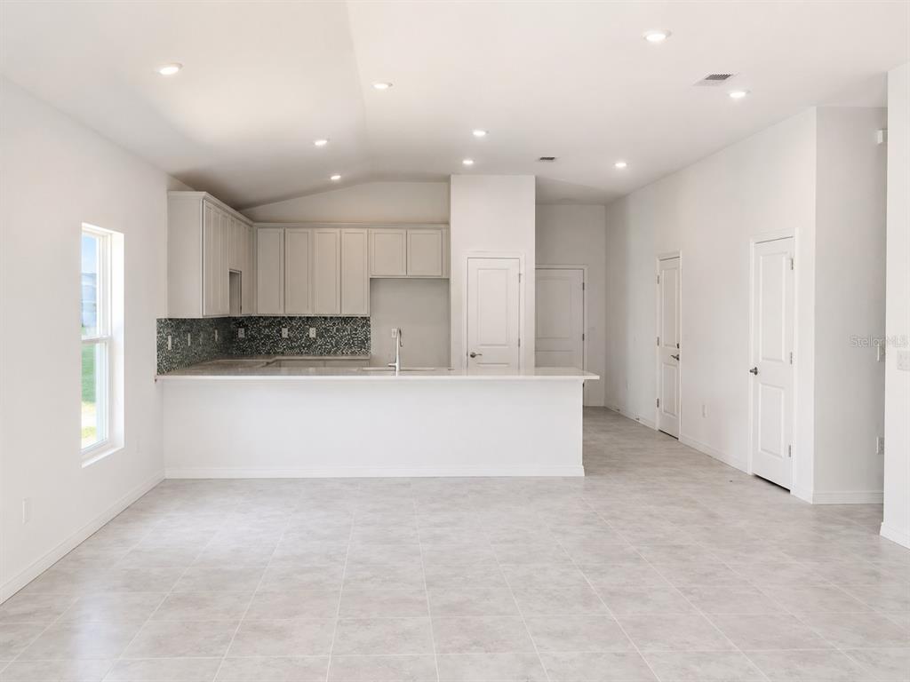 A kitchen with white cabinets, a tiled backsplash, and a breakfast bar island — 434 ALBATROSS ROAD, ROTONDA WEST, FL