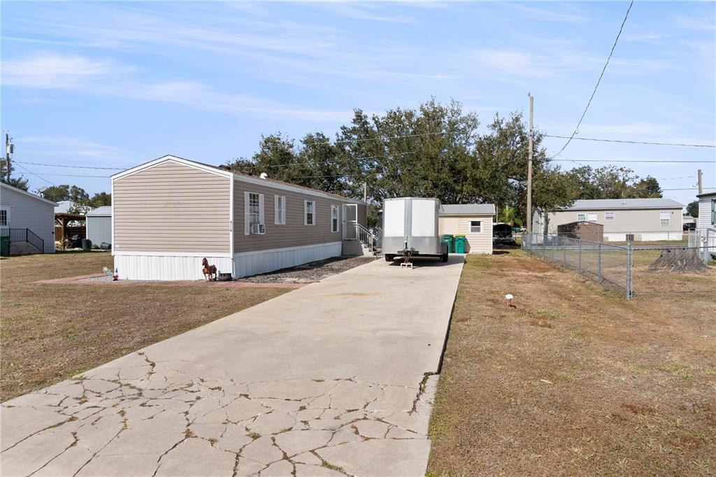 A beige mobile home with a concrete driveway and a trailer parked in the yard — 6526 JACK STREET, PUNTA GORDA, FL