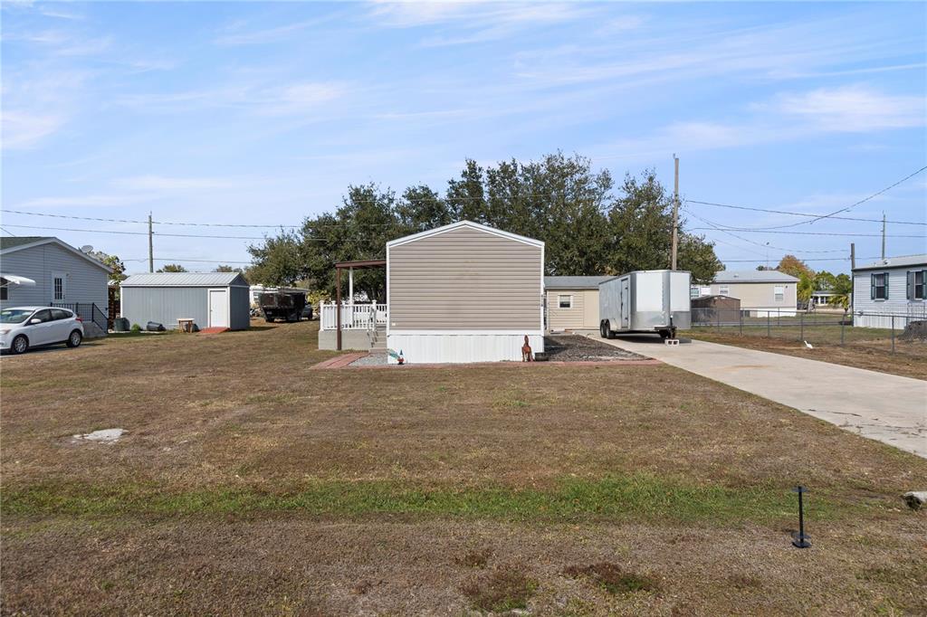 A single-story manufactured home with a concrete driveway and a detached shed — 6526 JACK STREET, PUNTA GORDA, FL