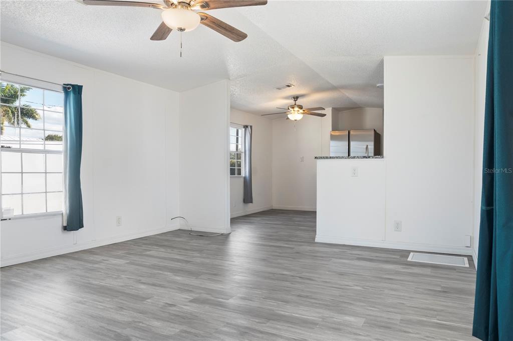 A living room with gray wood-look flooring, white walls, and two ceiling fans — 6526 JACK STREET, PUNTA GORDA, FL