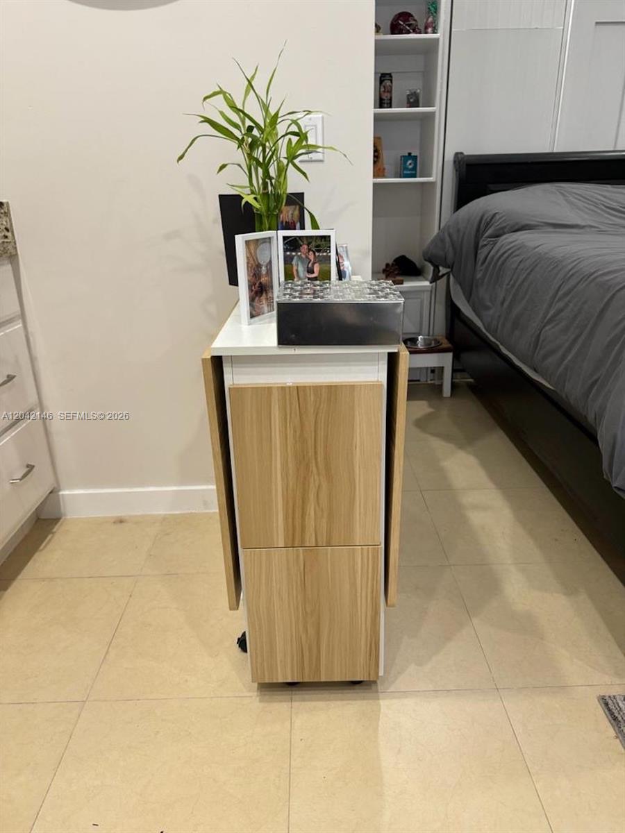 A bedroom features a light wood and white drop-leaf table positioned near a bed — 14234 SW 163rd Ter # 2, Miami FL 33177, MIAMI, FL