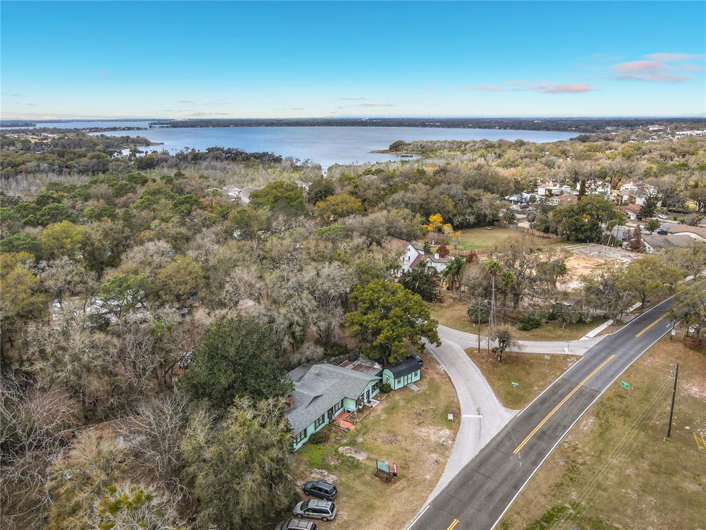 An aerial view shows a house nestled in a wooded area near a large lake — 6942 OLD HIGHWAY 441 S, MOUNT DORA, FL