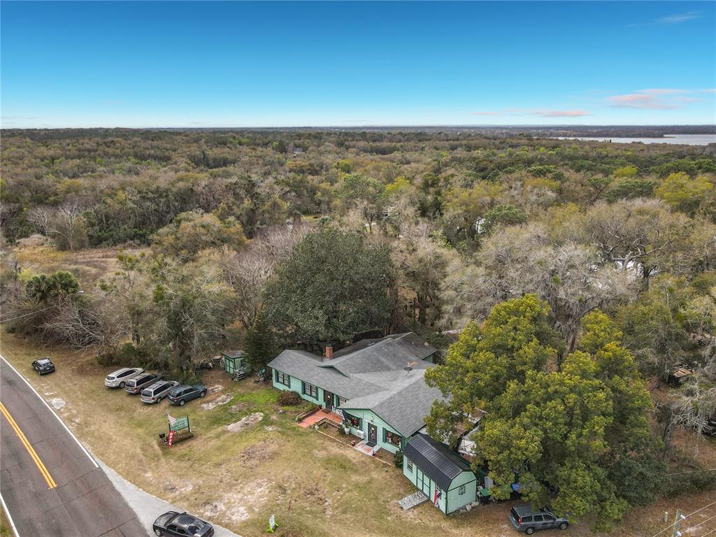 An aerial view shows a light green house with a gray roof near a road — 6942 OLD HIGHWAY 441 S, MOUNT DORA, FL