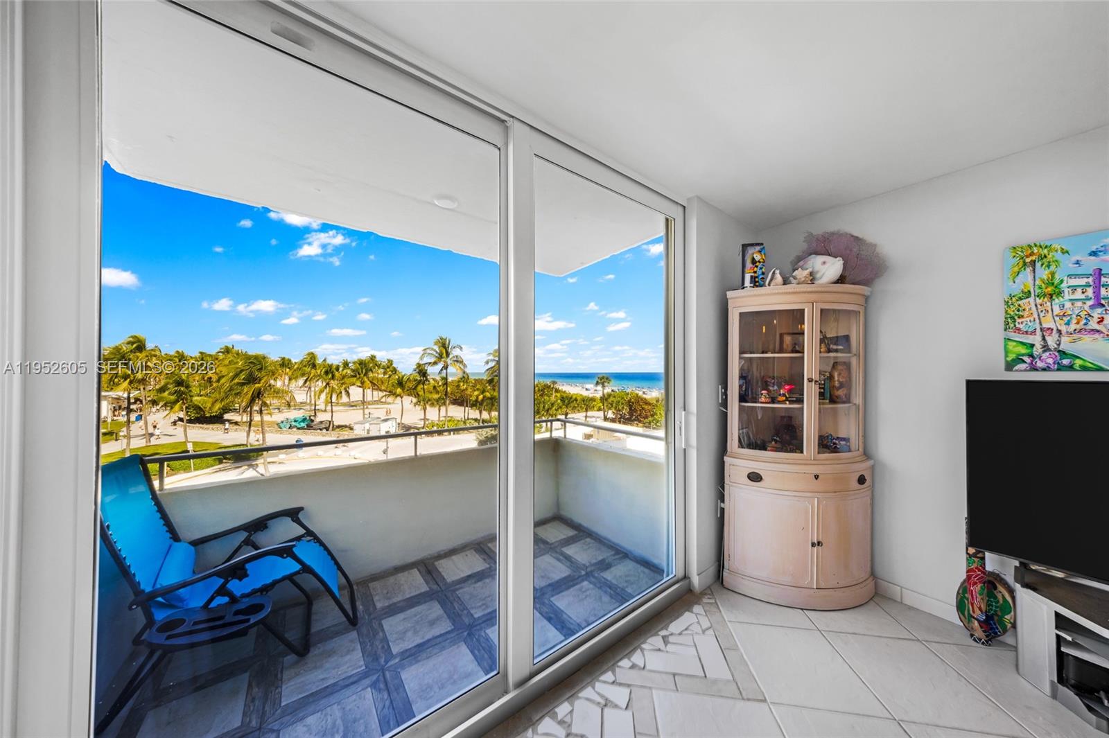 A living room with a balcony, a display cabinet, and a view of the beach — 465 Ocean Dr # 419, Miami Beach FL 33139, MIAMI BEACH, FL
