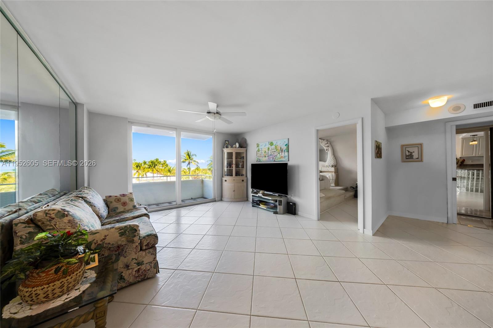 A living room features white tile floors, a floral sofa, and a sliding glass balcony door — 465 Ocean Dr # 419, Miami Beach FL 33139, MIAMI BEACH, FL