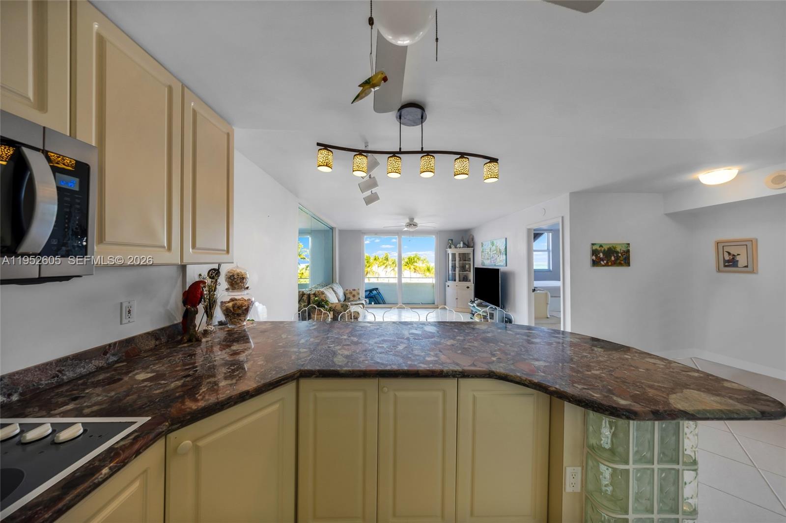 A kitchen with a curved granite countertop overlooks a living area with a balcony view — 465 Ocean Dr # 419, Miami Beach FL 33139, MIAMI BEACH, FL