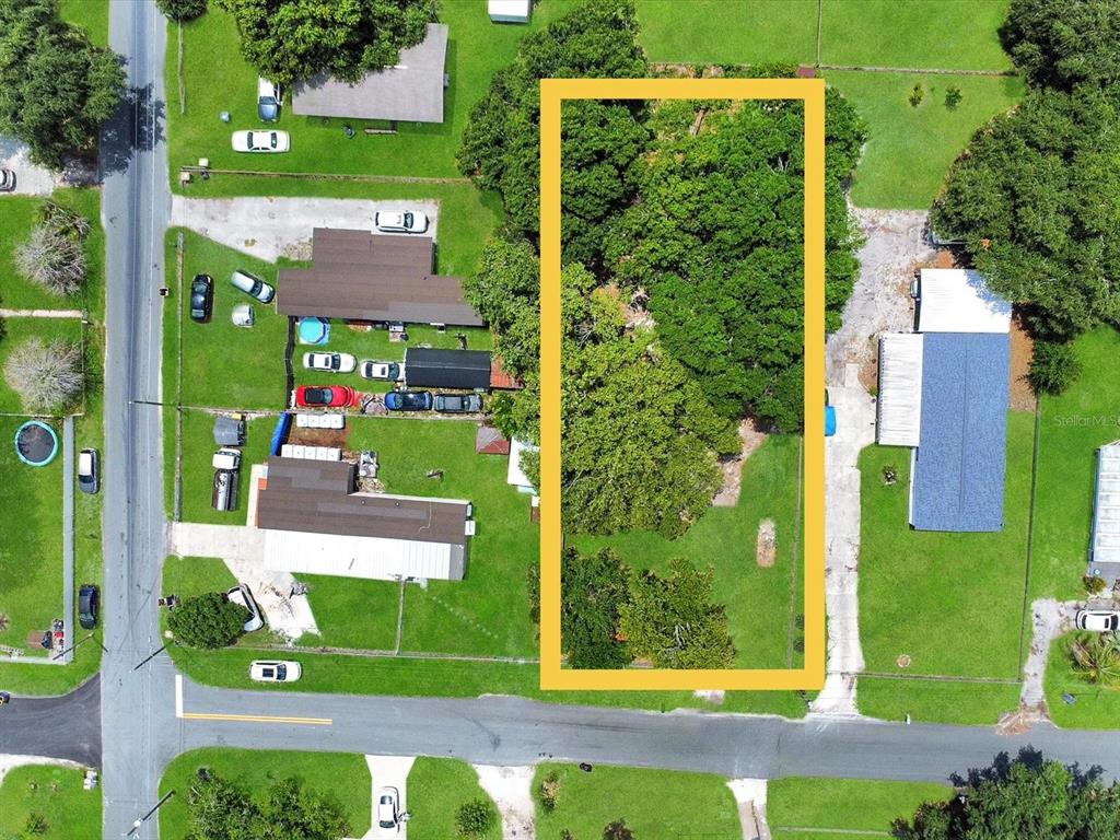 An aerial view shows a rectangular, tree-covered vacant lot outlined in yellow between two properties — 2824 BAY AVENUE, KISSIMMEE, FL