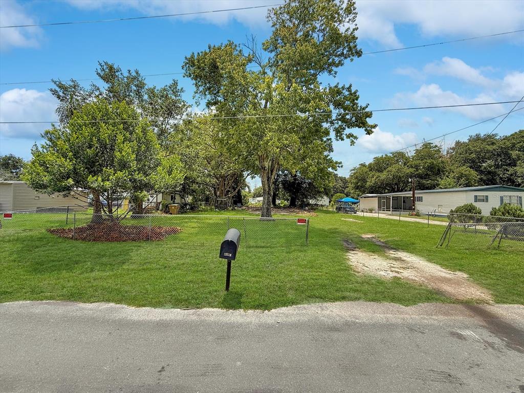 A grassy vacant lot features a mailbox, chain-link fencing, and several large mature trees — 2824 BAY AVENUE, KISSIMMEE, FL