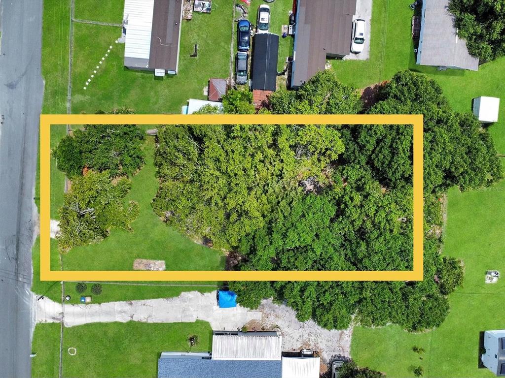 An aerial view shows a rectangular, tree-covered vacant lot outlined in yellow — 2824 BAY AVENUE, KISSIMMEE, FL