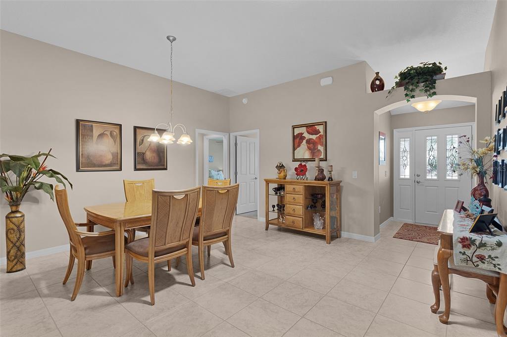 A dining room with tile floors, a wooden table, and an entryway with a front door — 1215 WESTMORELAND LOOP, THE VILLAGES, FL