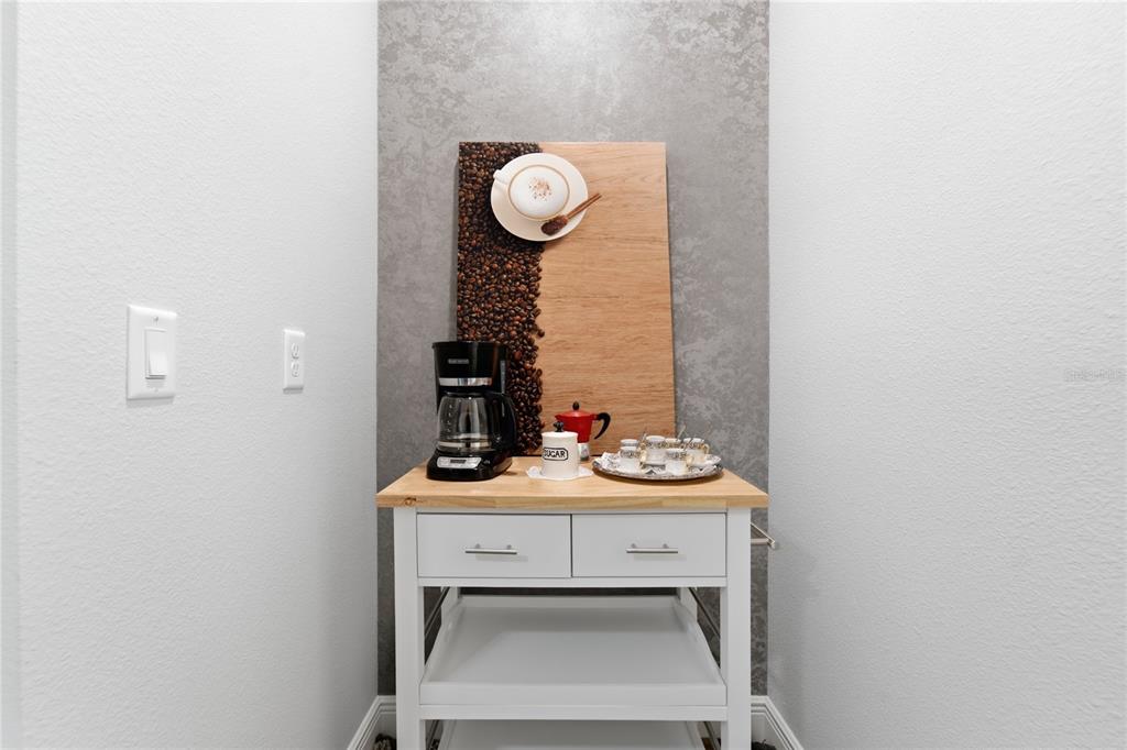 A white kitchen cart serves as a coffee station against a textured gray accent wall — 9083 SUNSHINE RIDGE LOOP, KISSIMMEE, FL
