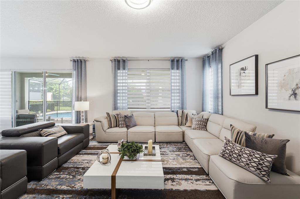 A living room features a large beige sectional, a dark leather sofa, and a coffee table — 9083 SUNSHINE RIDGE LOOP, KISSIMMEE, FL