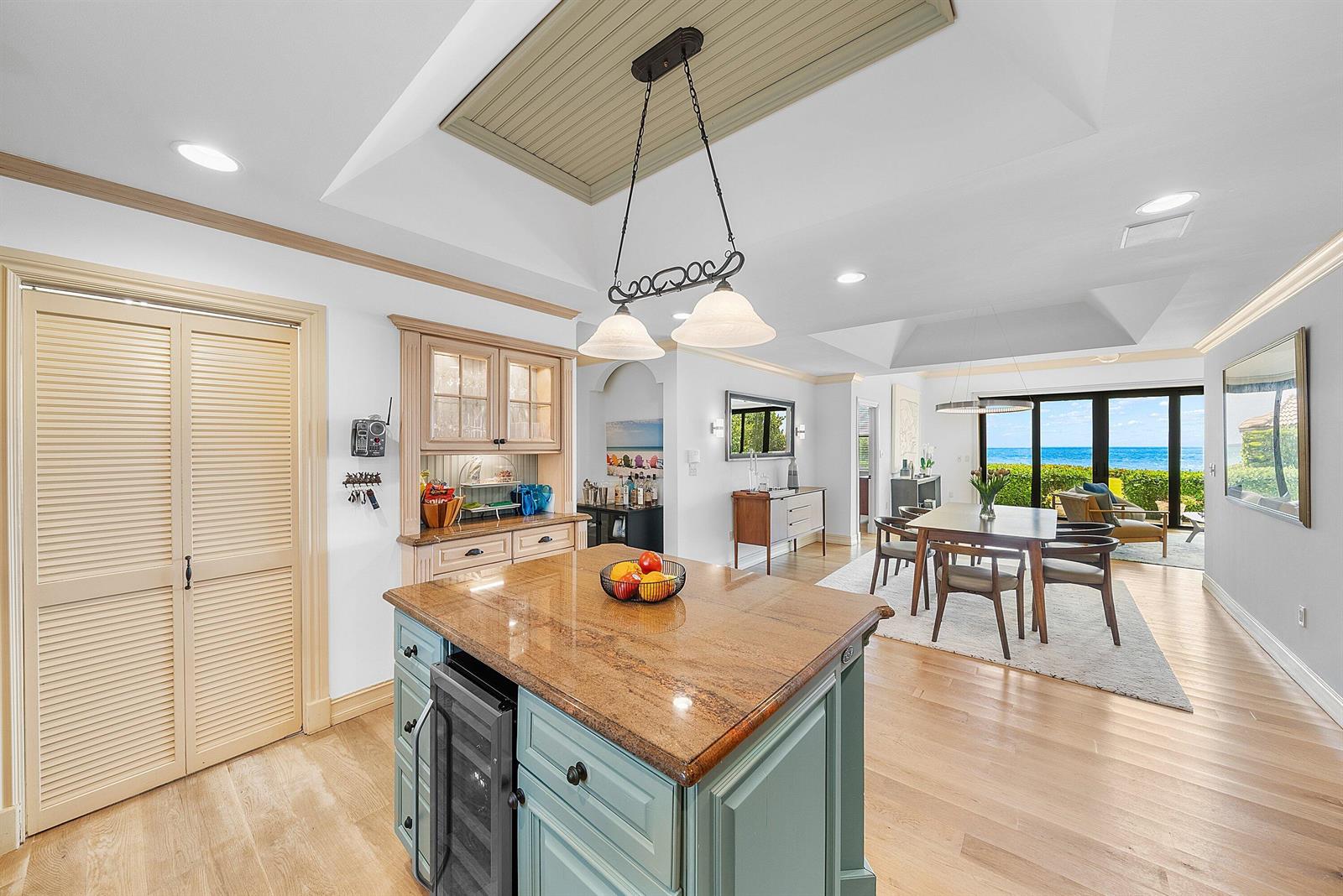 A kitchen island with a granite countertop sits before a dining area overlooking the ocean — 3951 N Ocean Boulevard # 101, Gulf Stream FL 33483, GULF STREAM, FL