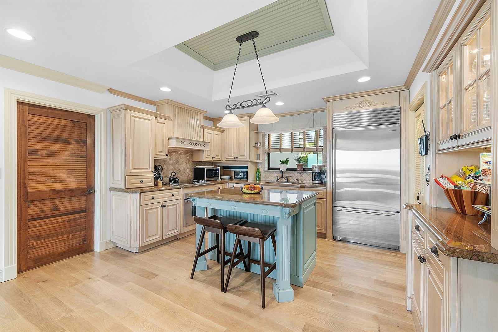 A kitchen features light wood cabinets, a blue island with bar stools, and stainless appliances — 3951 N Ocean Boulevard # 101, Gulf Stream FL 33483, GULF STREAM, FL