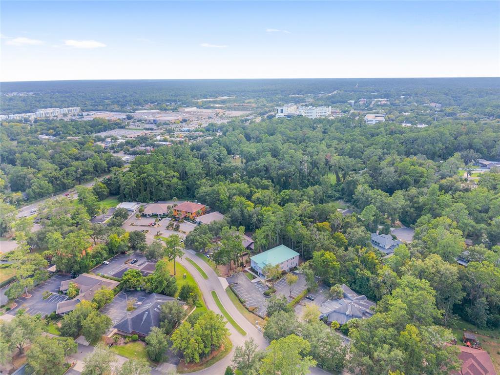 An aerial view shows several commercial buildings surrounded by dense trees and parking lots — 1014 NW 57TH STREET, GAINESVILLE, FL