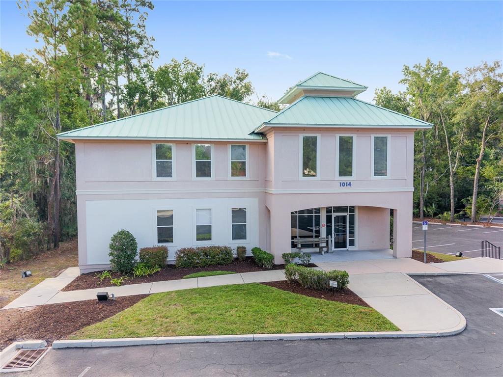 A two-story commercial building with a green metal roof and a light-colored stucco exterior — 1014 NW 57TH STREET, GAINESVILLE, FL