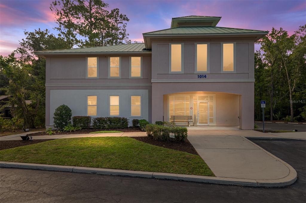 A two-story commercial building with a metal roof, light-colored stucco exterior, and a covered entrance — 1014 NW 57TH STREET, GAINESVILLE, FL