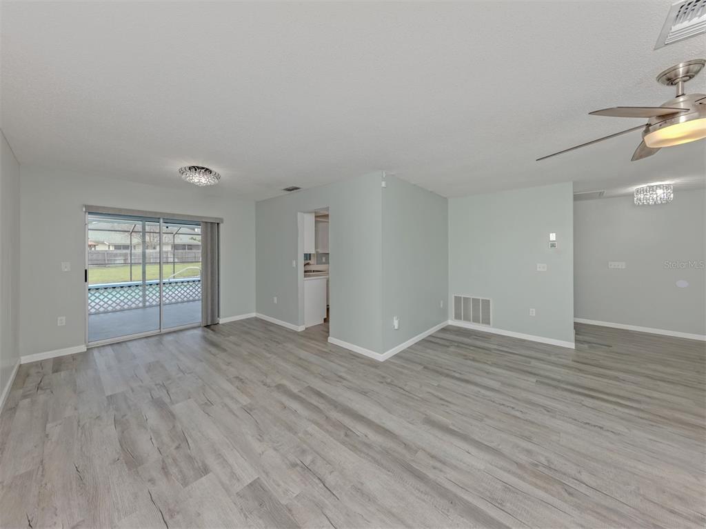 An empty room features light gray walls, wood-look flooring, a ceiling fan, and sliding glass doors — 1053 DERIAN PLACE, NOKOMIS, FL