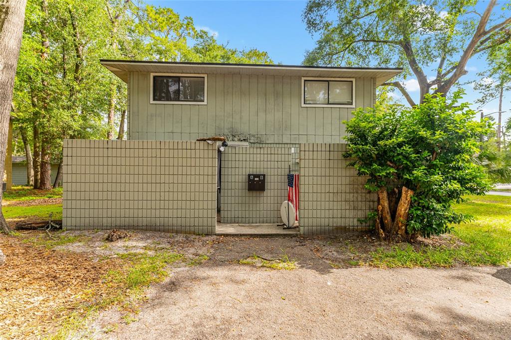 A two-story building with vertical siding sits behind a low, tan concrete block wall — 714 SW 69TH STREET, GAINESVILLE, FL