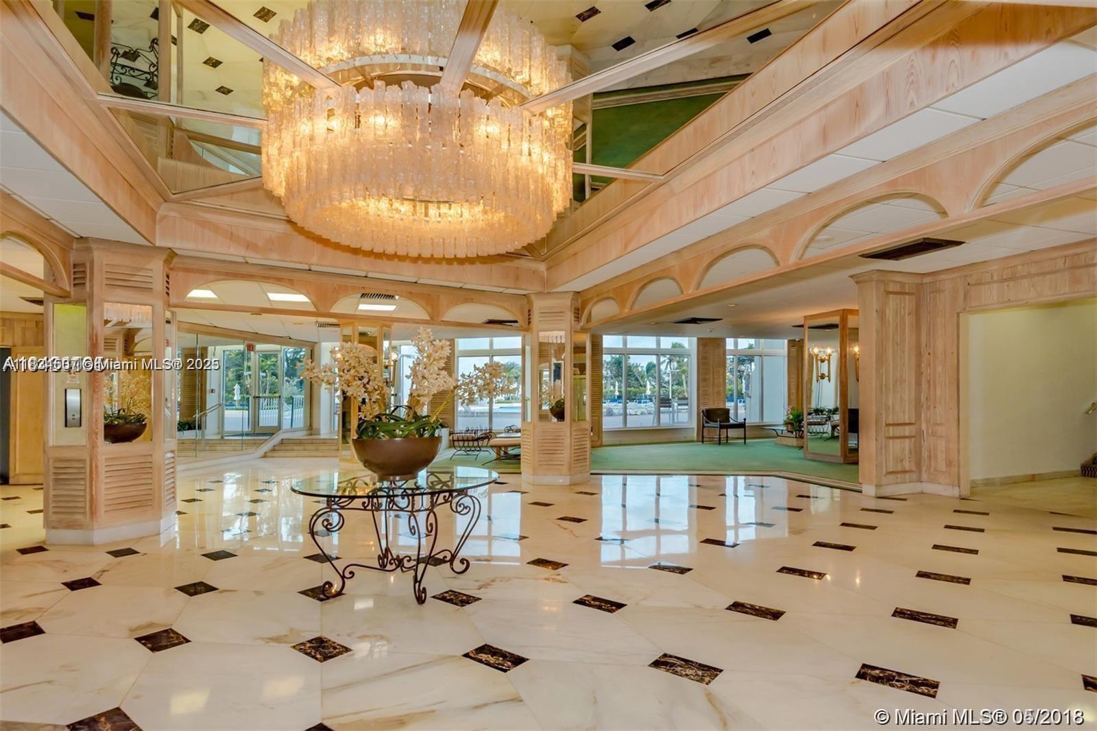 A spacious lobby features a large crystal chandelier, marble flooring, and light wood paneling — 3180 S Ocean Dr # 1602, Hallandale Beach FL 33009, HALLANDALE BEACH, FL
