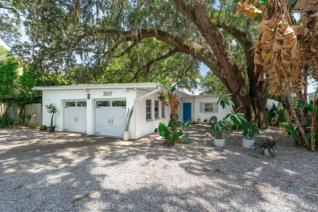 A single-story house with a two-car garage, gravel driveway, and large oak tree in front — 3107 LAKE MARGARET DRIVE, ORLANDO, FL