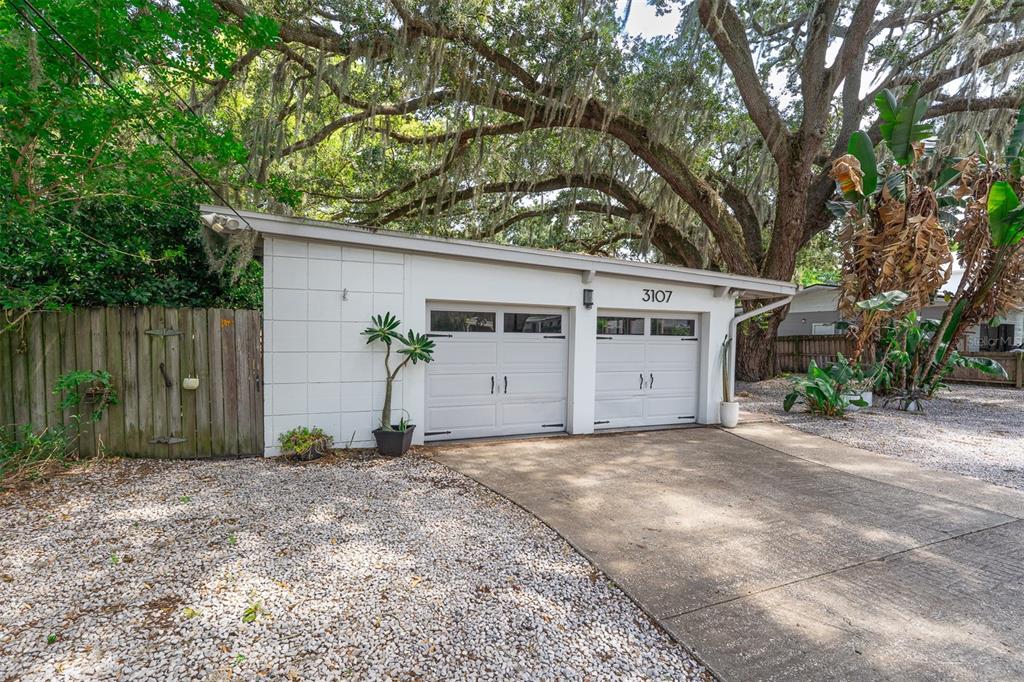 A grassy backyard features a stone fire pit, two benches, and a wooden dock on a lake — 3107 LAKE MARGARET DRIVE, ORLANDO, FL